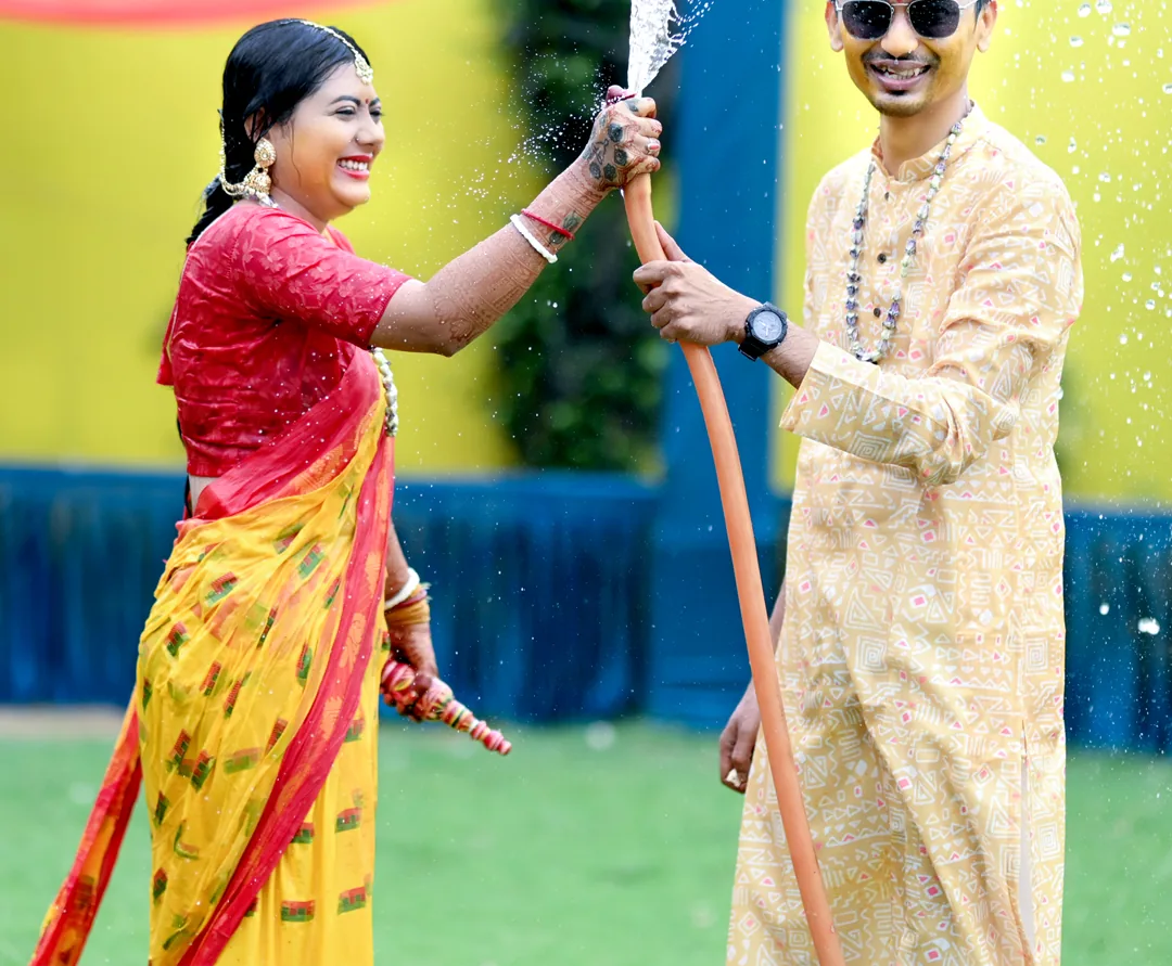 Couple playing with water during a haldi celebration
