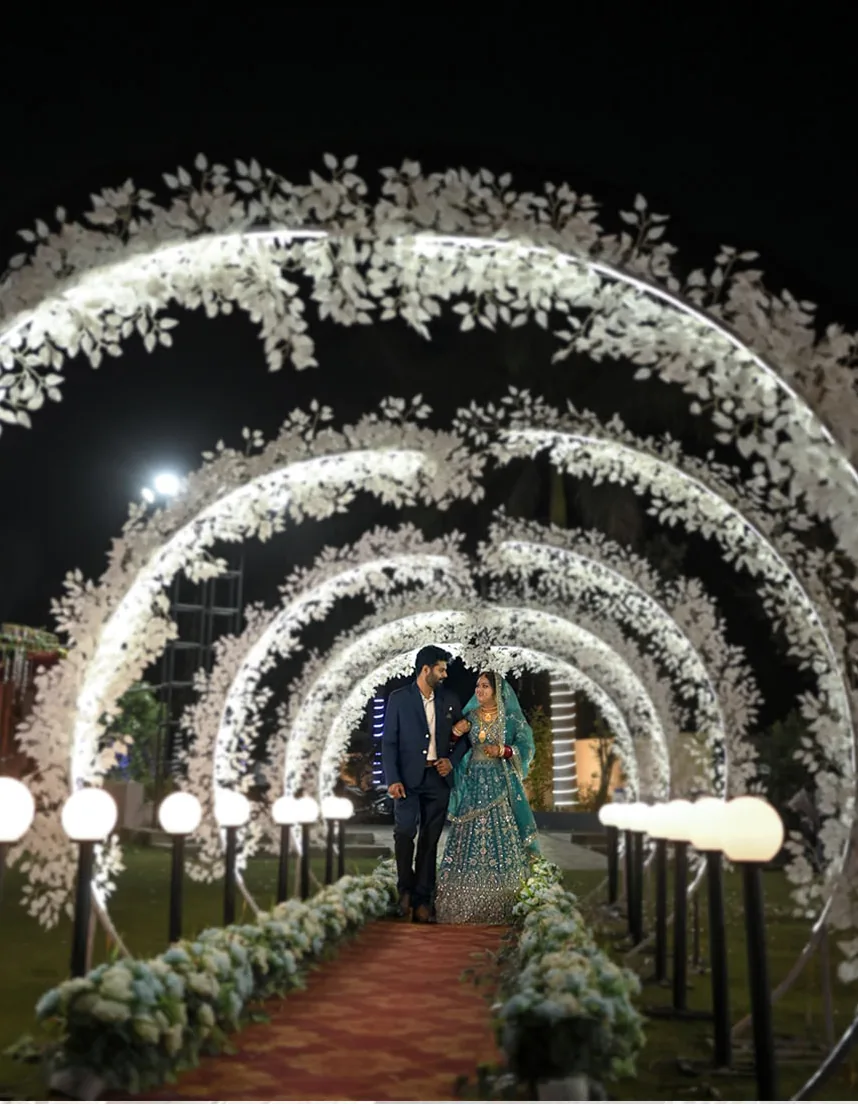 Couple walking through an illuminated floral tunnel at night