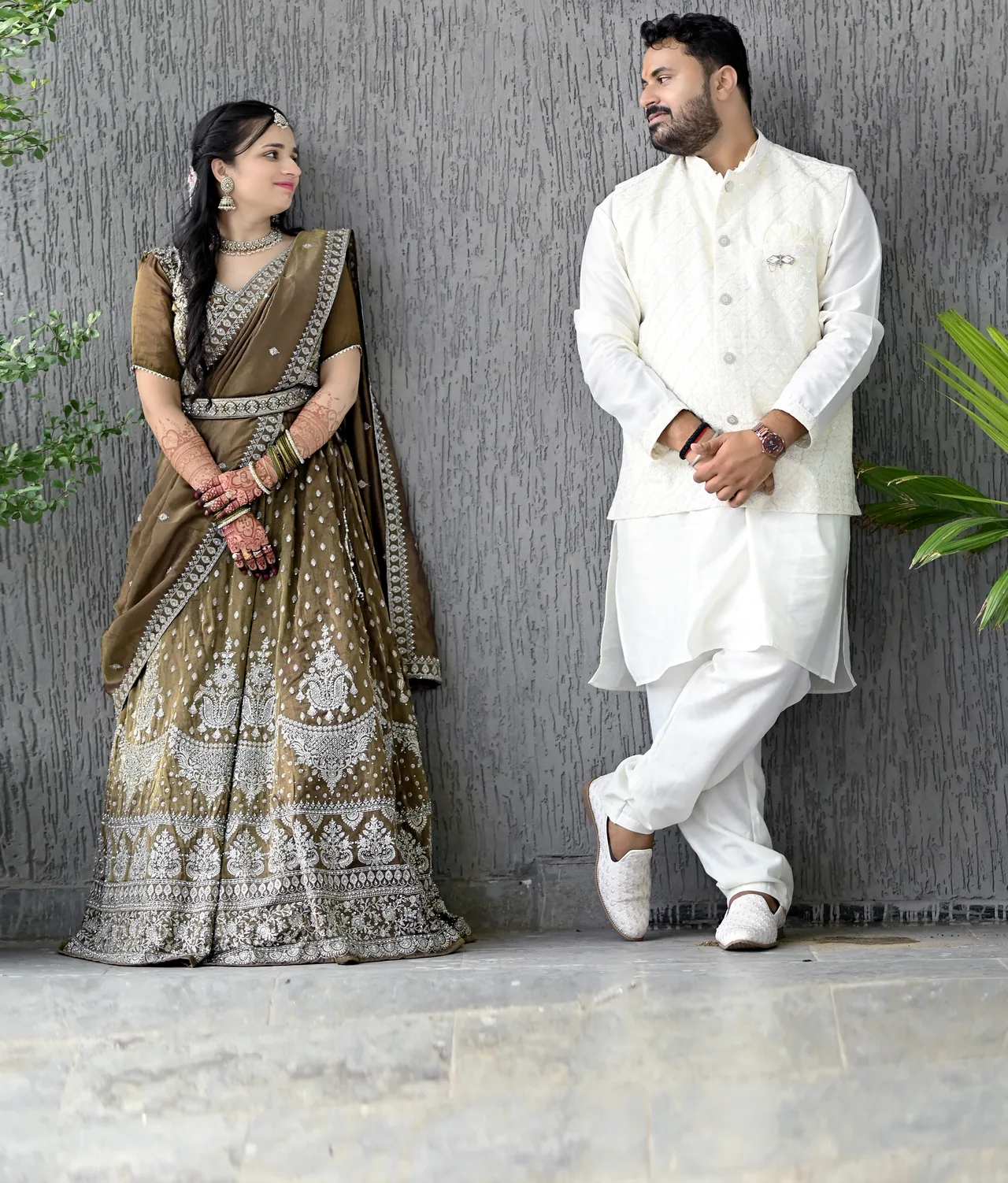 Couple in traditional outfits posing against a grey wall