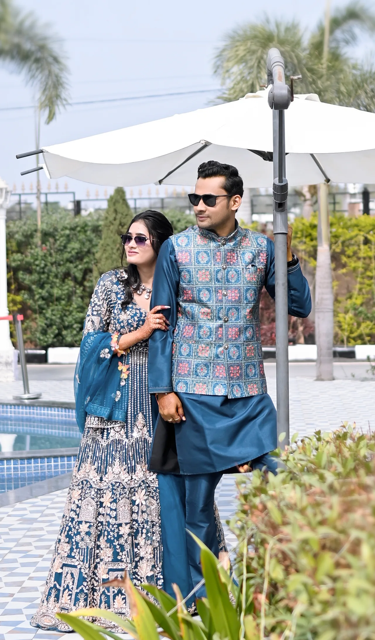 Couple in coordinated blue outfits standing by a poolside