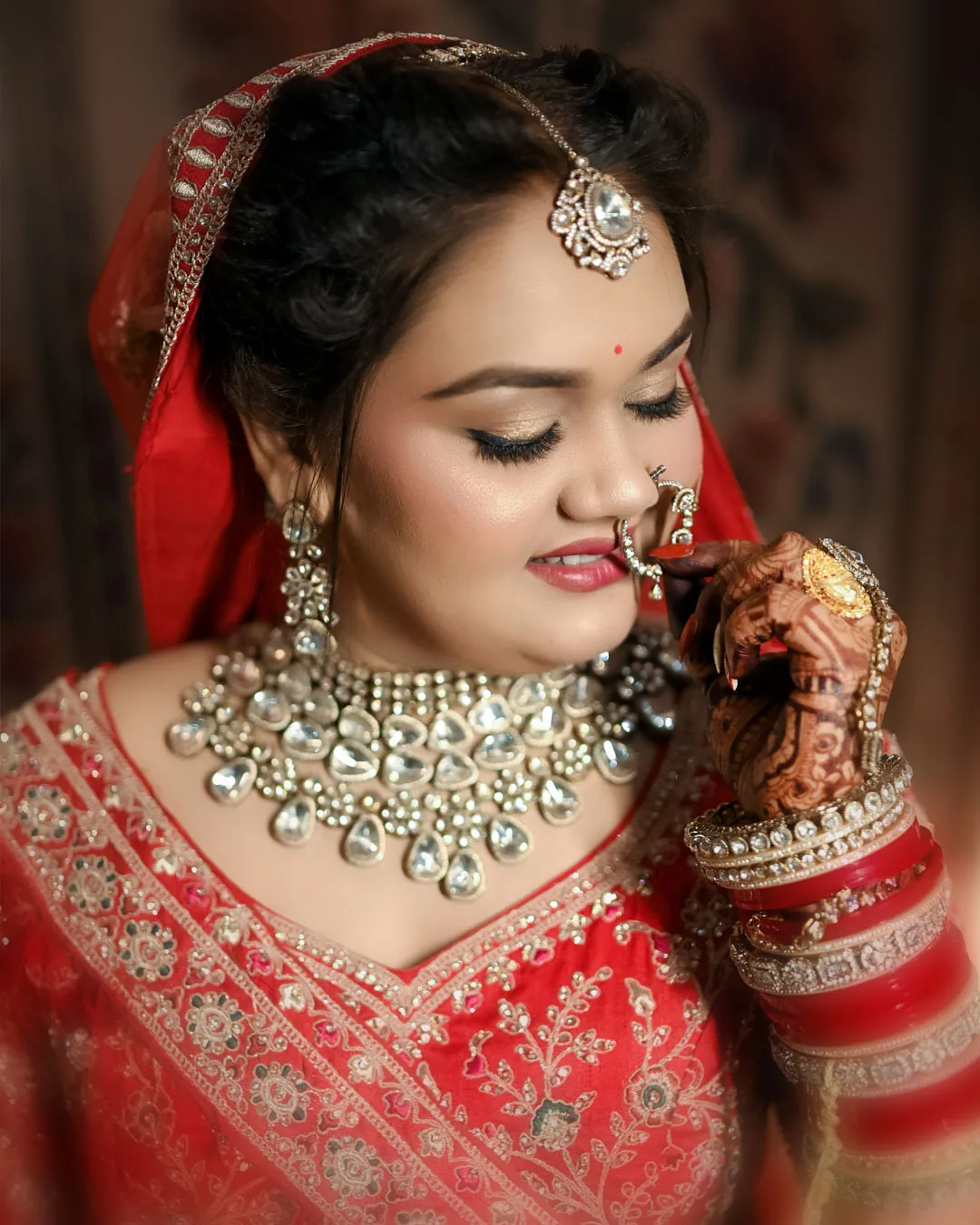 Close portrait of a bride in kundan jewellery holding her nath