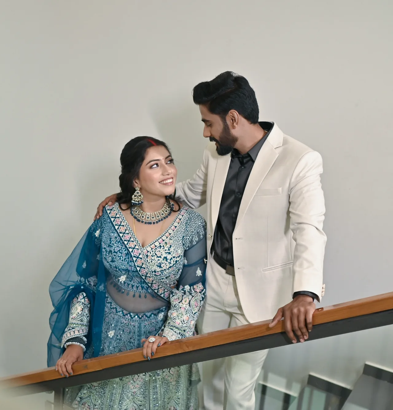 Couple by a staircase, the woman in a blue lehenga