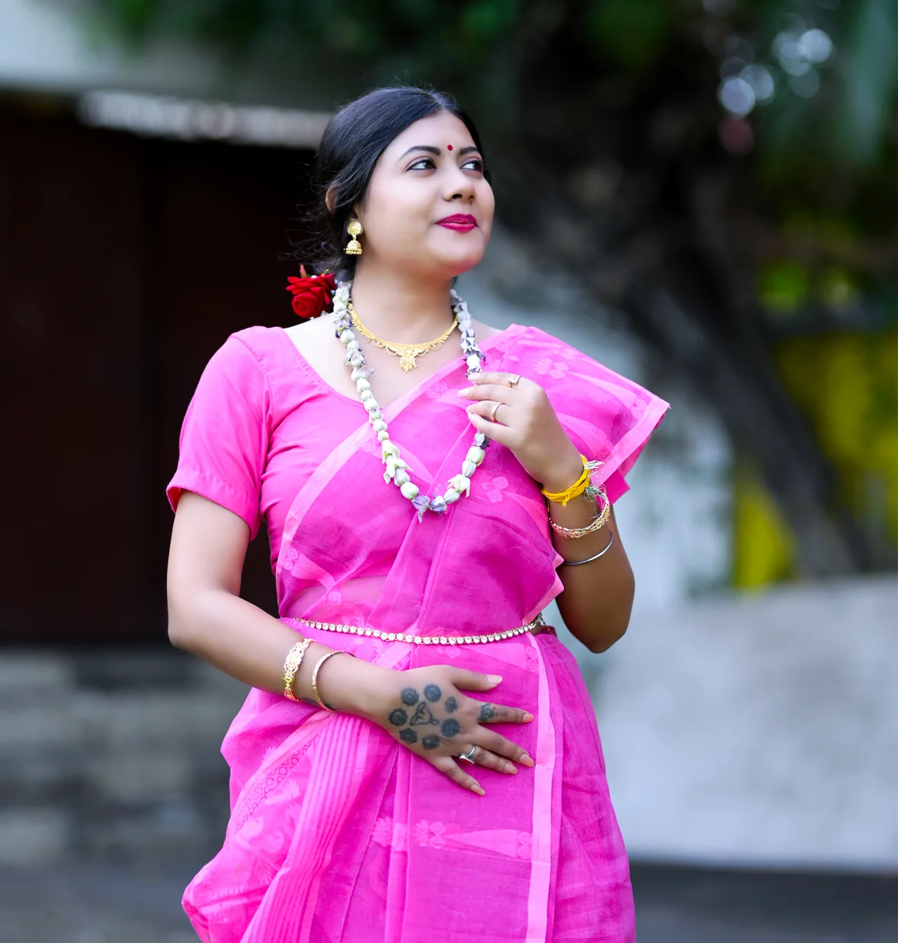 Portrait of a woman in a pink saree and floral jewellery