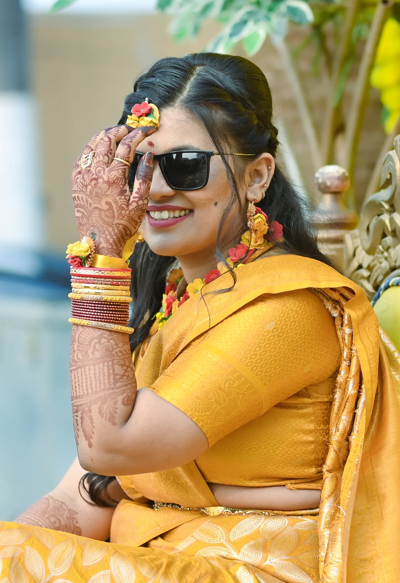 Bride in a yellow saree and sunglasses at her haldi