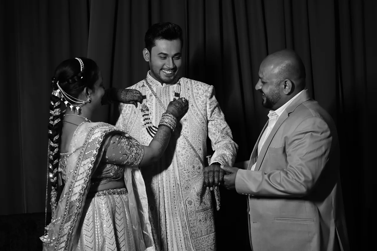Family helping the groom get ready, in black and white