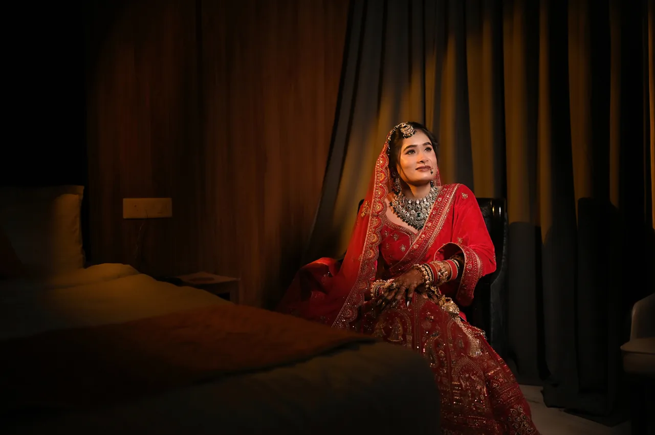 Bride in red seated in a softly lit room