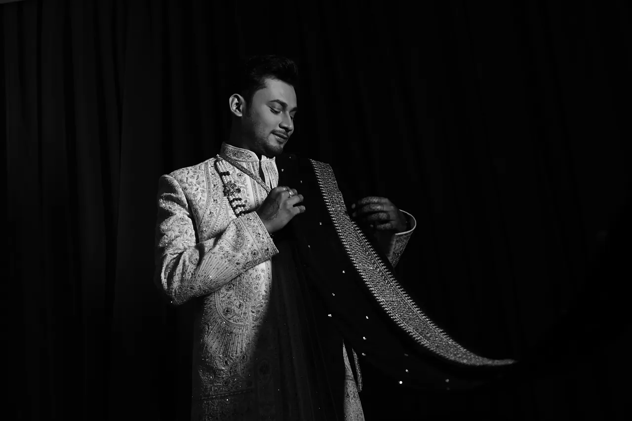 Black-and-white portrait of a groom adjusting his stole