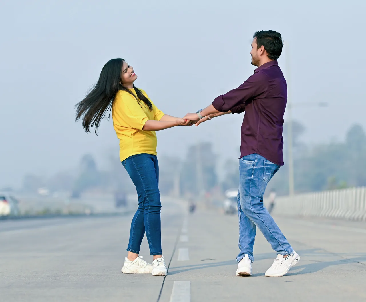 Couple holding hands and laughing on an open road