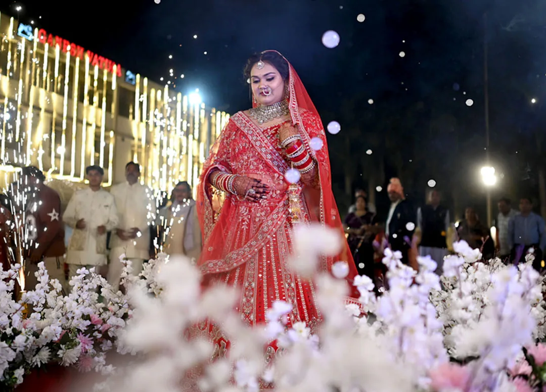 Bride making her entrance at night, surrounded by lights and flowers