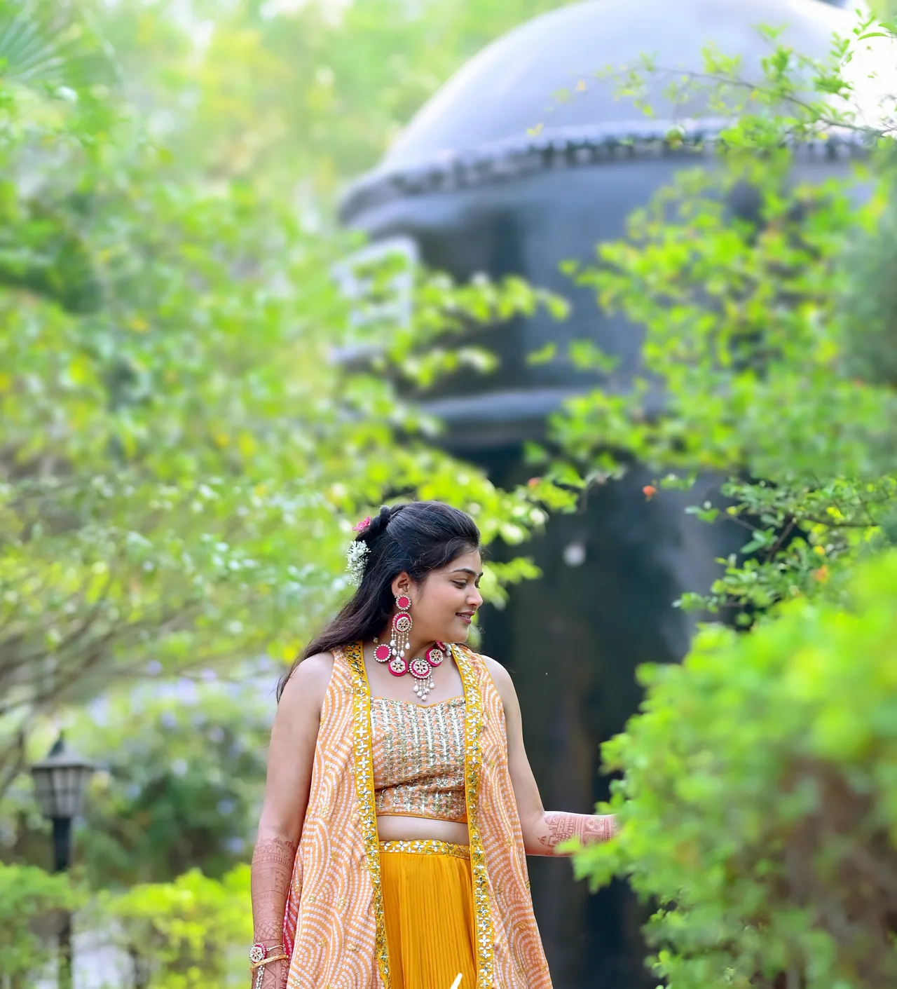 Woman in a mustard lehenga walking along a garden path