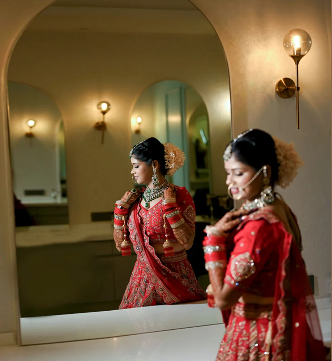 Bride in red looking at her reflection in an arched mirror